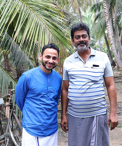Two men standing together in a coconut grove in India
